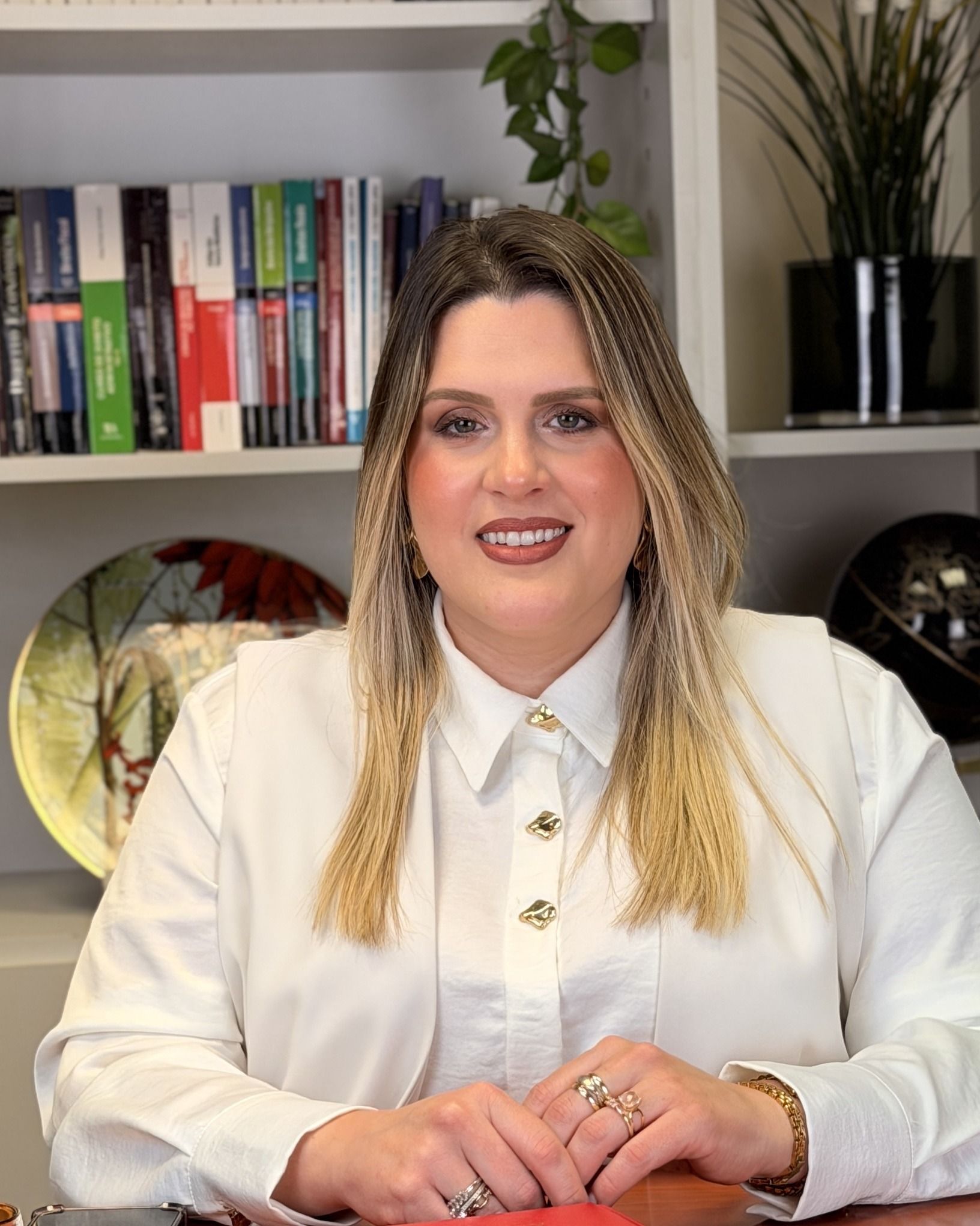 Nádia Vilela à secretária, em frente a uma estante de livros de Direito